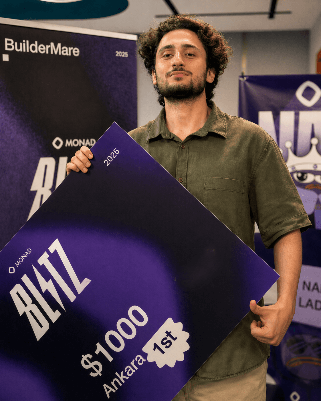 Alperen Manas holding the Monad Blitz first-place prize board at the hackathon venue.